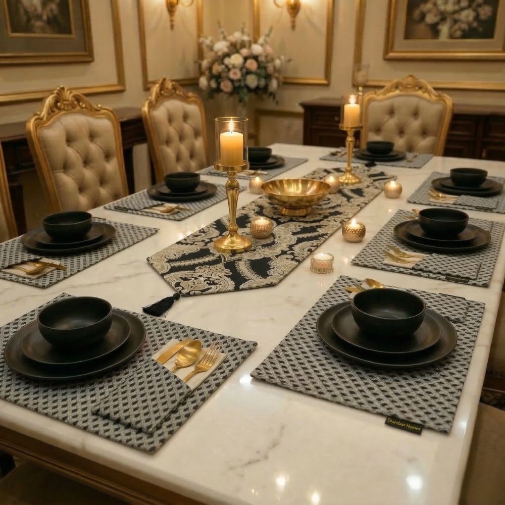 Elegant dining table set with black plates, gold candle holders, and decorative candles in a formal setting.