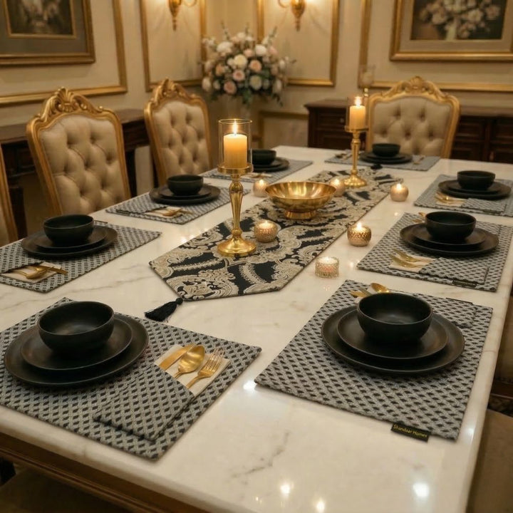 Elegant dining table set with black plates, gold candle holders, and decorative candles in a formal setting.
